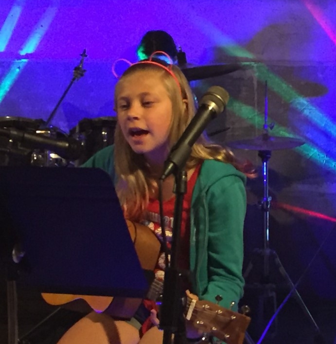 Zoe is singing and playing guitar during the jam session-She is now playing in the school jazz bands